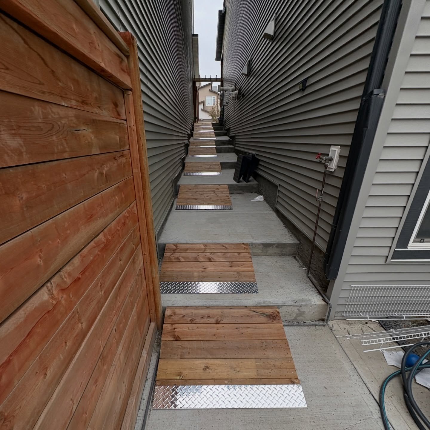 Custom wheelchair-accessible wood ramps with metal transition plates along a side-yard walkway