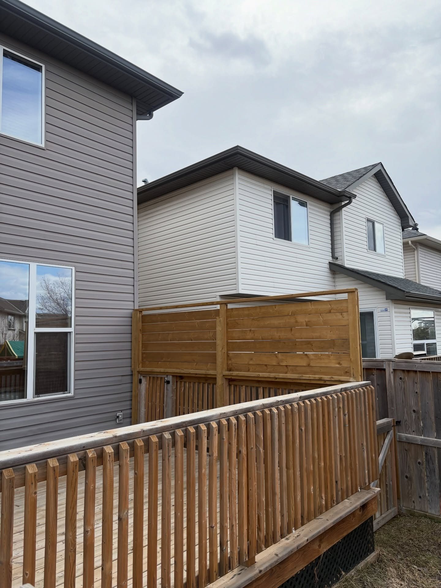 Wood deck railing and horizontal privacy screen beside a Calgary home