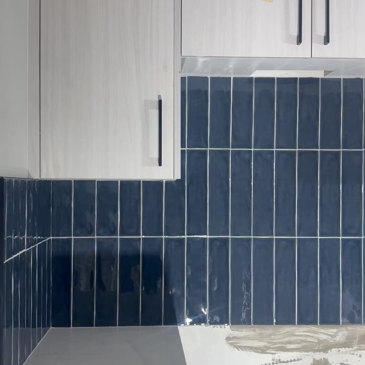 Close-up of glossy navy vertical kitchen backsplash tiles and white grout